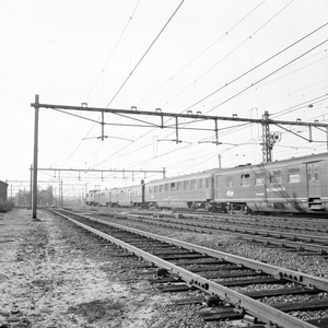 883130 Afbeelding van een trein bestaande uit rijtuigen plan D en plan E, getrokken door een electrische locomotief uit ...